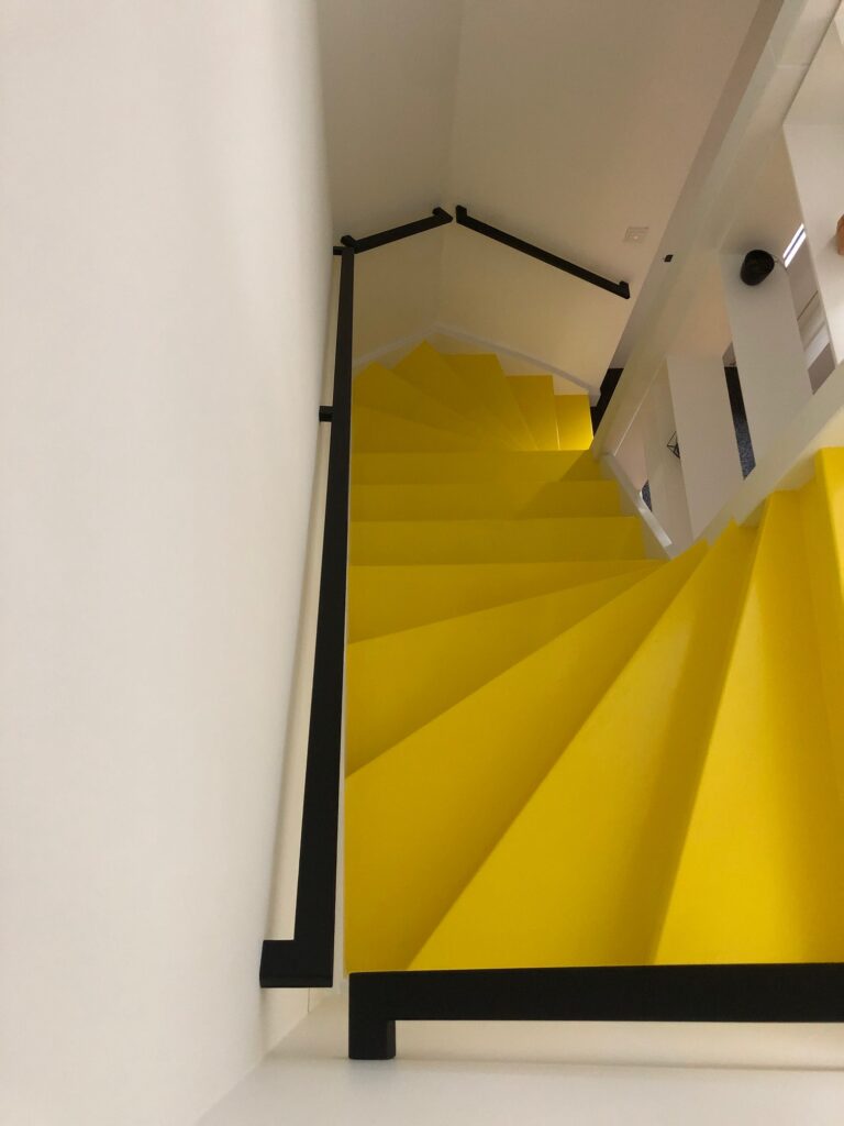 Trap verven in de kleur geel met stalen trapleuningen design