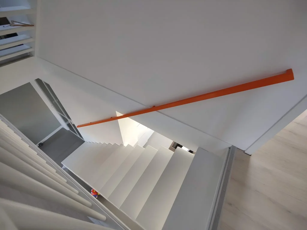 oranje design trapleuning bij een witte stalen open trap