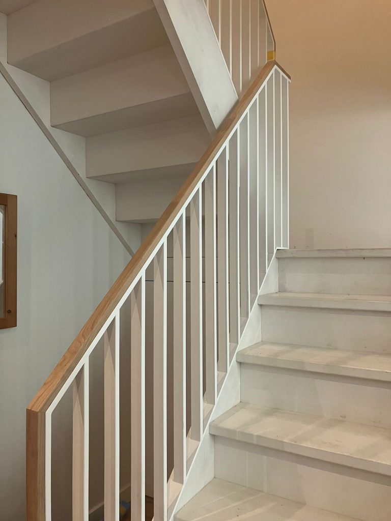 Witte stalen design balustrade met verticale strips en massief eikenhouten trapleunign