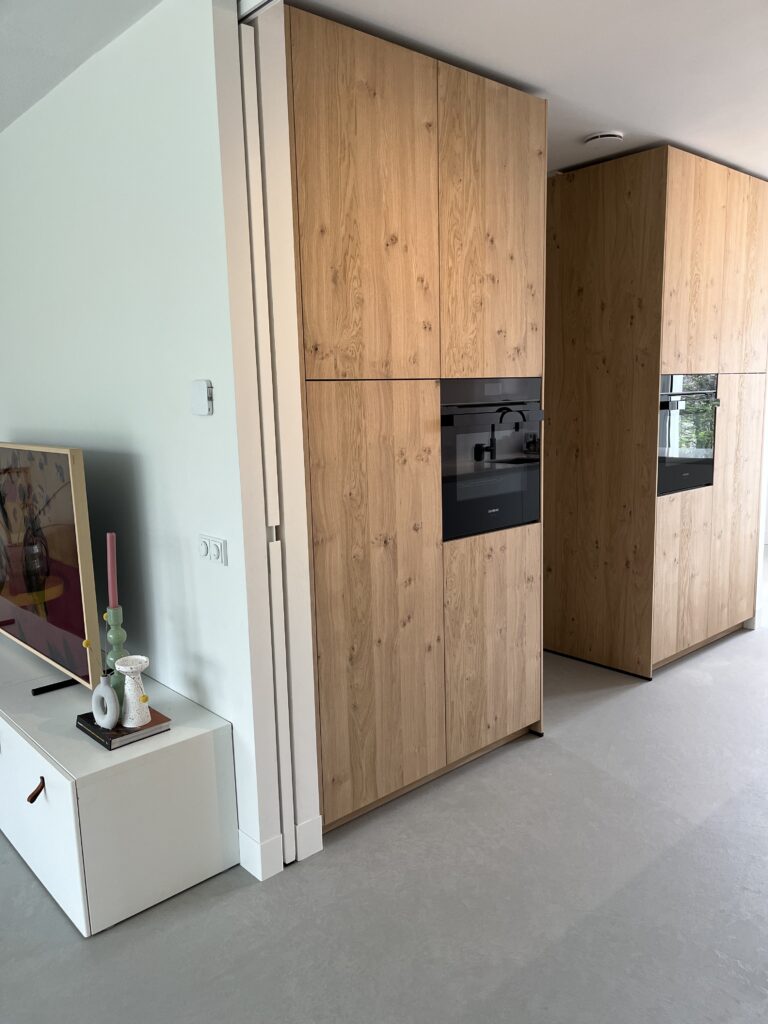 Witte stalen schuifdeur tussen woonkamer en keuken, volledig glas met soft close aan beide kanten en design handgreep. Design schuifdeur weggewerkt in de muur